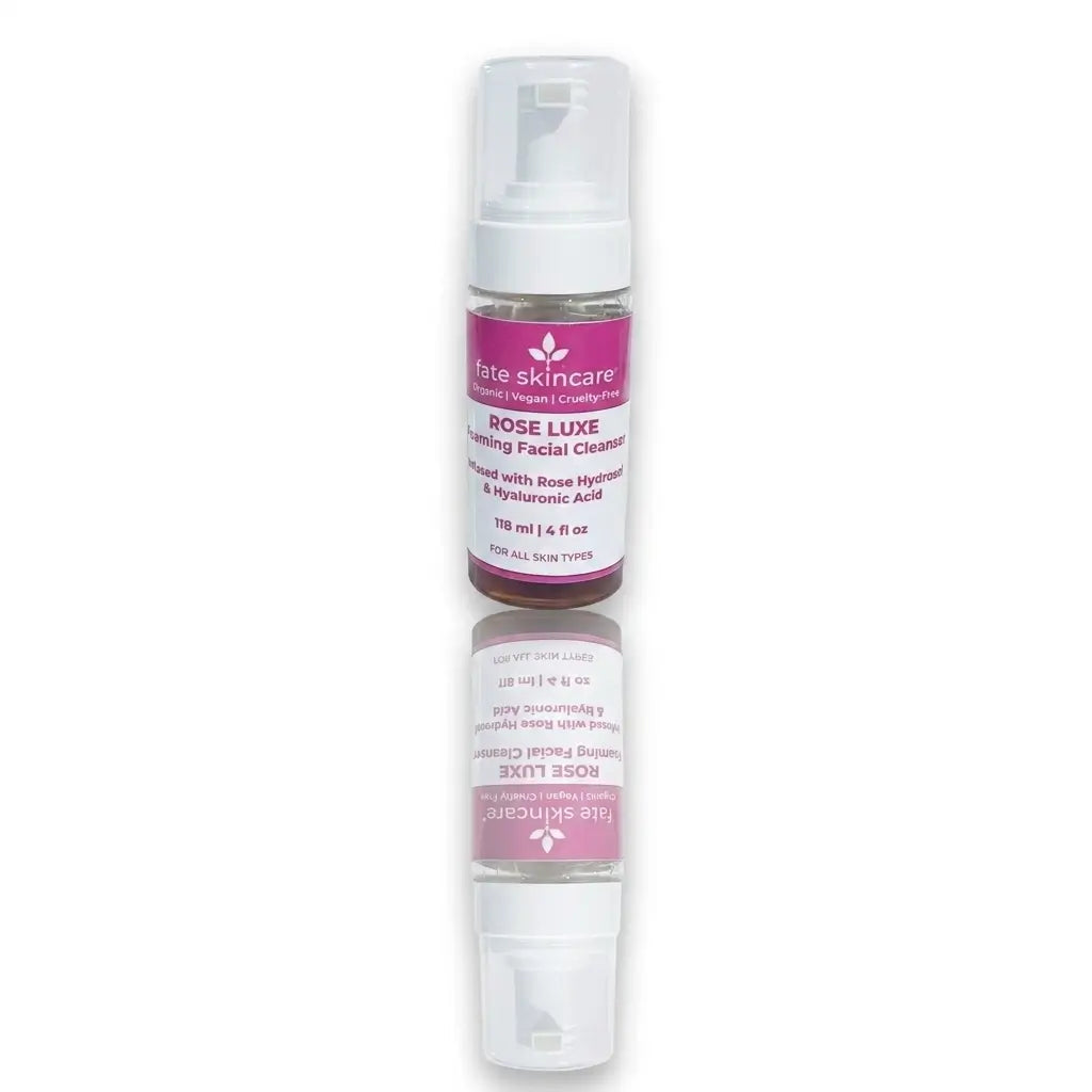 A vertical product shot of a Fate Skincare Rose Luxe Foaming Facial Cleanser bottle, labeled as organic and vegan, with its reflection mirrored directly below on a white background.