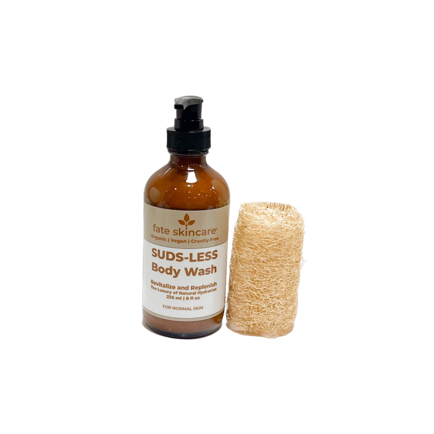 A bottle of Fate Skincare's Suds-Less Body Wash in an amber glass pump bottle, labeled for normal skin, positioned beside a natural loofah sponge on a clean white background. The label reads “Revitalize and Replenish – The Luxury of Natural Hydration.”