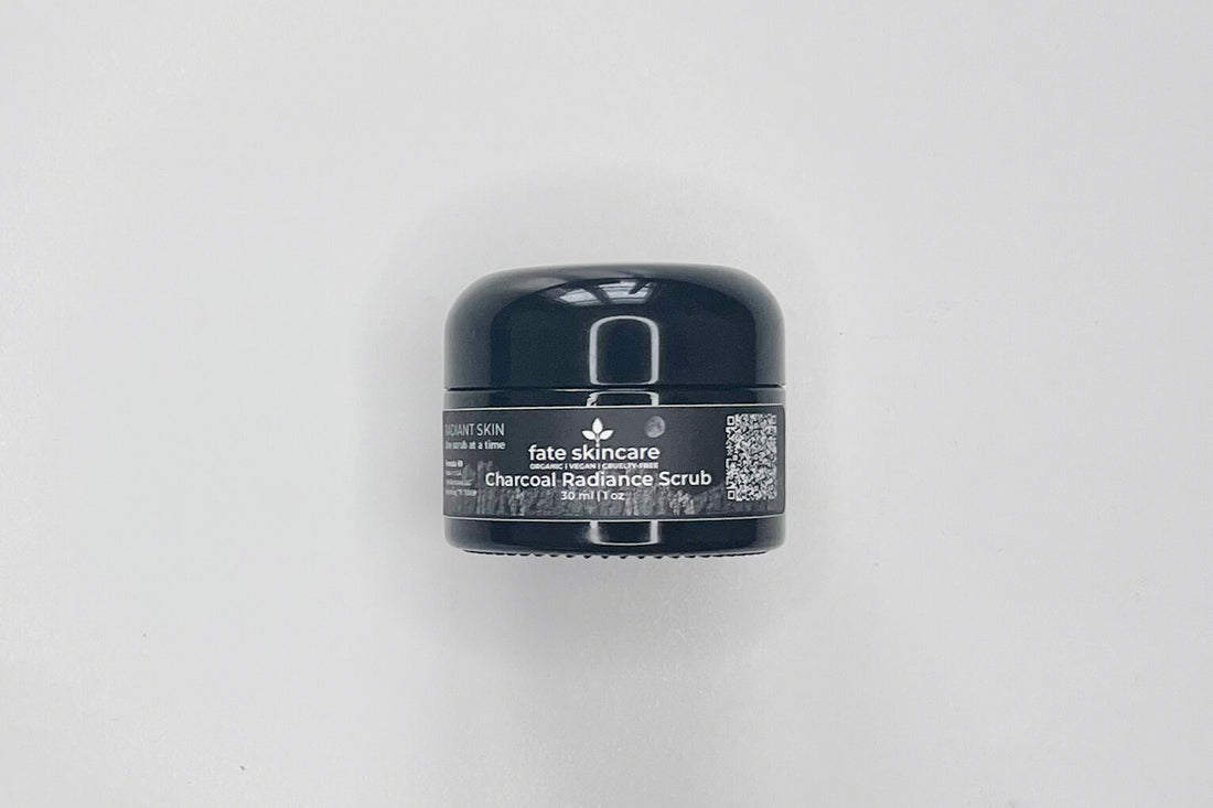 An image of Fate Skincare's Charcoal Radiance Scrub, in a black glass cosmetic container, with a black label, with wite writing and the iconic Fate Skincare logo.  
