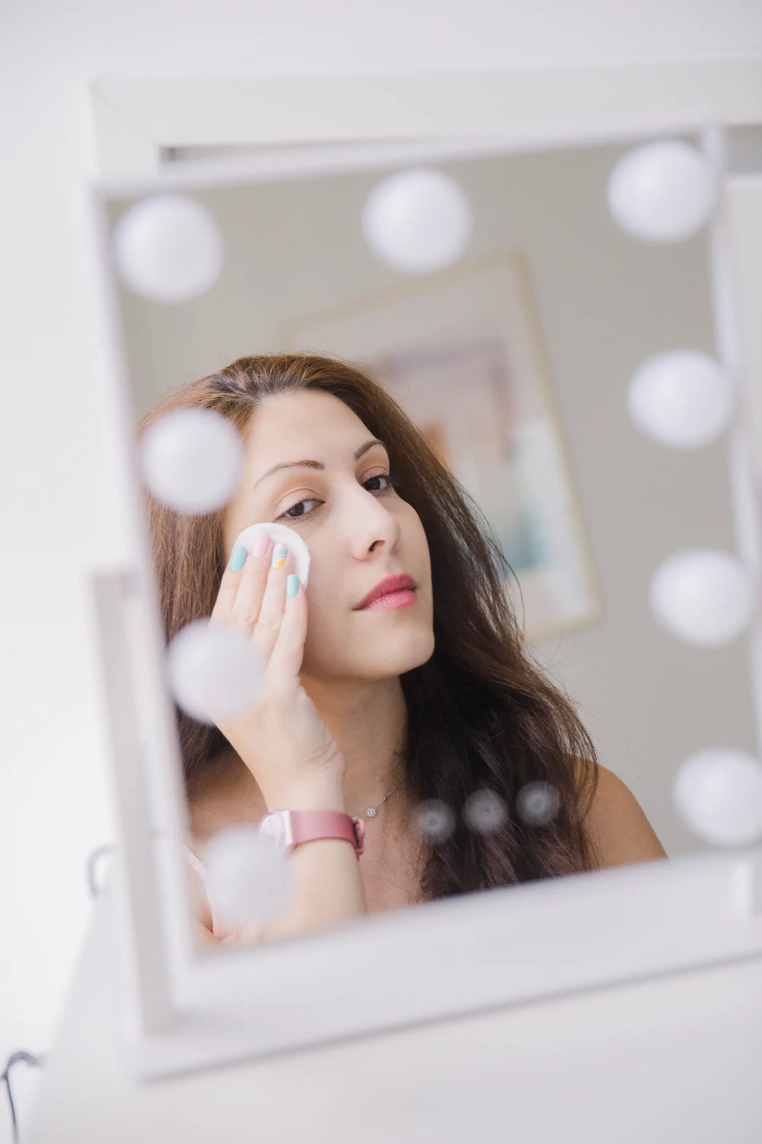 Woman looking in the mirror and applying Fate Skincare's ACV toner to her face