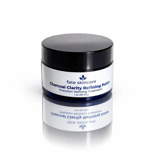 Fate Skincare Charcoal Clarity Refining Polish in cobalt blue glass jar with black lid on a reflective surface for sensitive and eczema-prone skin