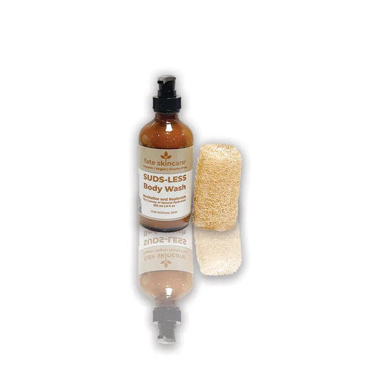 Suds-Less Body Wash by Fate Skincare in an amber pump bottle with natural loofah, crafted as a gentle, herbal-based body cleanser that revitalizes and replenishes skin.